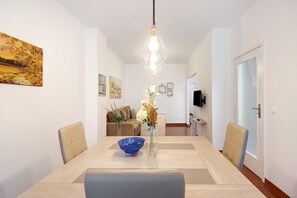 Un espace repas comprenant une table, des chaises, un vase avec des fleurs et un luminaire suspendu.