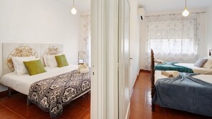 Ein Schlafzimmer mit zwei Betten, einer gemusterten Tagesdecke und einem Spiegel.