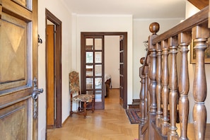 Un escalier en bois avec une rampe, une chaise et une porte donnant sur une autre pièce.