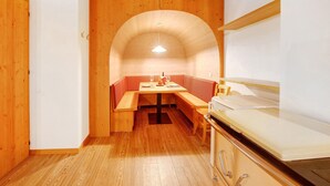 A compact kitchen with wooden cabinets, a built-in bench, and a small dining table. - Holiday Apartment "Tra-Monti E Mare" with Mountain View, Private Terrace & Sauna (Valdidentro)