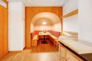 A compact kitchen with wooden cabinets, a built-in bench, and a small dining table.