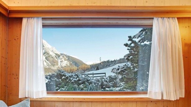 A wooden interior with a large window overlooking a snowy mountain landscape. - Holiday Apartment "Tra-Monti E Mare" with Mountain View, Private Terrace & Sauna (Valdidentro)