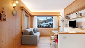A cozy room with a sofa, a dining table, and a TV. - Holiday Apartment "Tra-Monti E Mare" with Mountain View, Private Terrace & Sauna (Valdidentro)