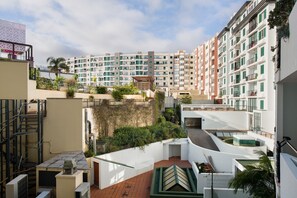 Un immeuble résidentiel à plusieurs étages, doté de balcons, d’une terrasse sur le toit et offrant une vue sur les bâtiments voisins.