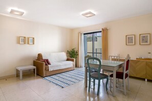 Un salon comprenant un canapé, une table à manger, des chaises, un banc et un tapis à motifs.