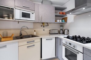 A modern kitchen with a microwave, toaster, sink, and stove.