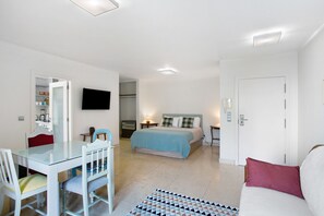 A room with a bed, a TV, a dining table, and a sofa.