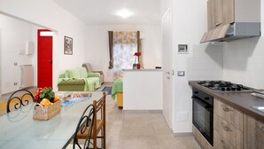 Une cuisine compacte équipée d’une cuisinière à gaz, d’un four et d’un coin repas avec une table et des chaises.