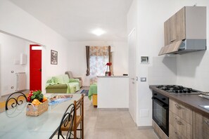 Une cuisine compacte équipée d’une cuisinière à gaz, d’un four et d’un coin repas avec une table et des chaises.