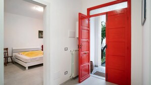Une chambre à coucher avec un lit, un radiateur, une porte rouge et un mur blanc.
