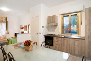 Una cucina moderna con un tavolo da pranzo in vetro, mobili in legno e una finestra con vista.
