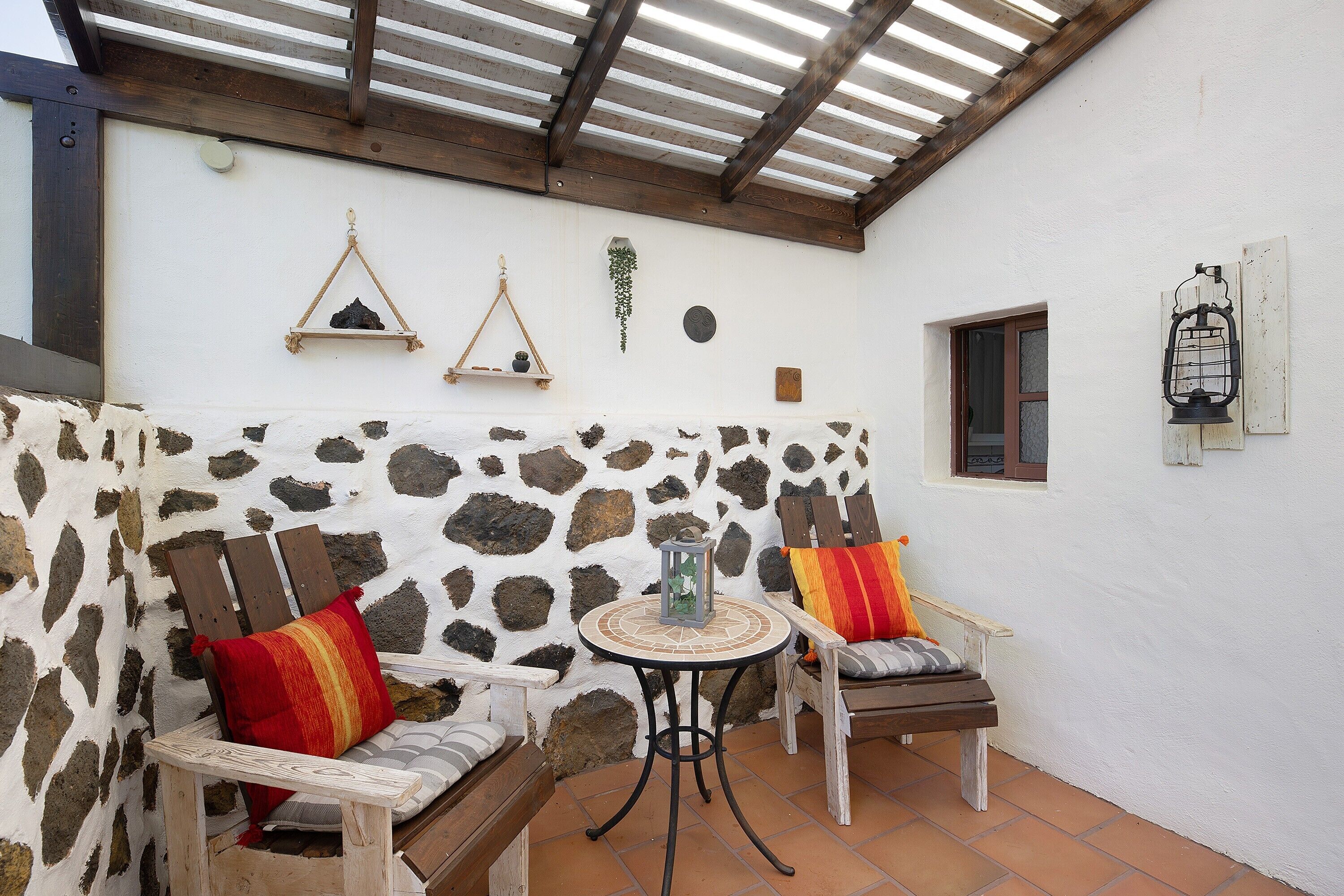 Une terrasse avec deux chaises en bois, une petite table ronde et une lanterne.