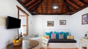 Una habitación con cama, televisión, mesa de comedor y sillas, y ventana.