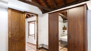 Ein Flur mit Holztüren, Fliesenboden und einem Bett im Hintergrund.
