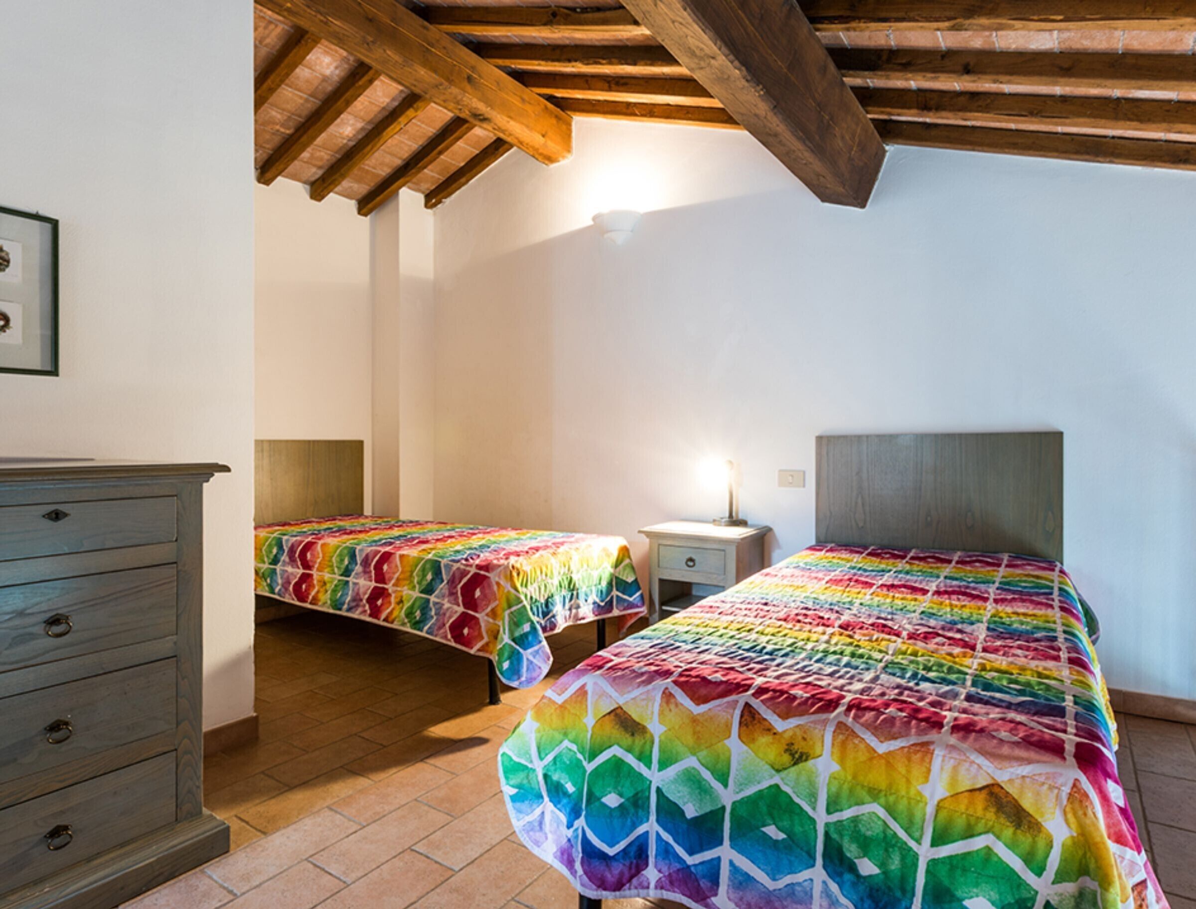 Una habitación con dos camas, un aparador y una mesita de noche con lámpara.