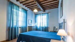 A bedroom with a bed, a nightstand, a lamp, and a window with curtains. - Holiday Home 'Podere Simonetta - A2' with Shared Pool, Private Terrace and Wi-Fi (Cecina)