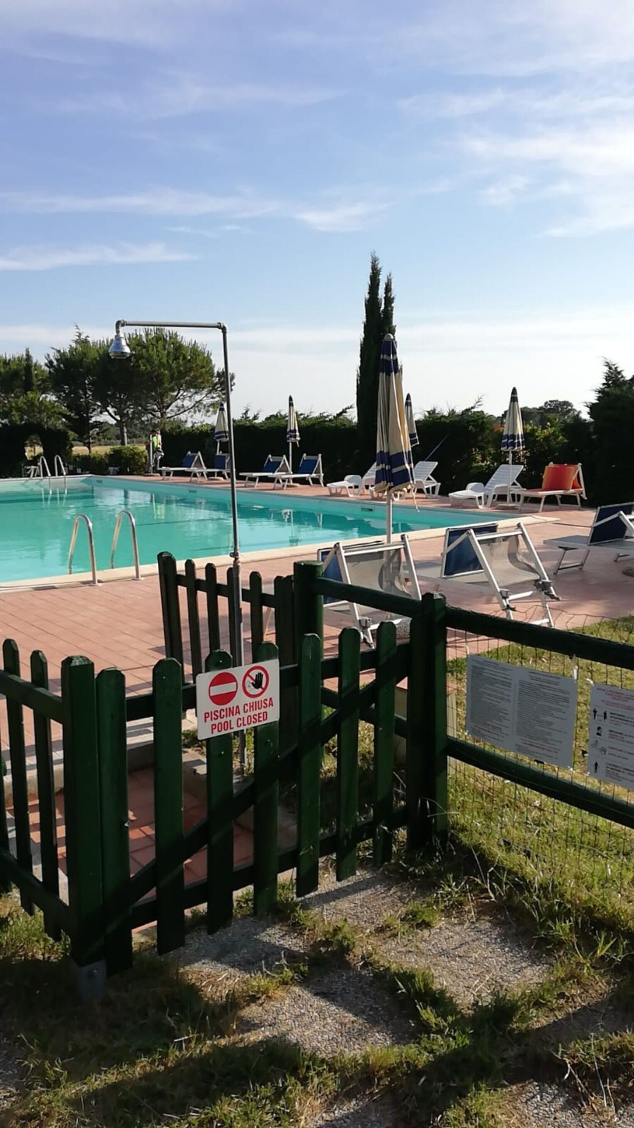A swimming pool with lounge chairs and a closed pool sign.