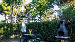 A patio with a table and chairs, a grill, and a hedge. - Holiday Home 'Podere Simonetta - A11' with Shared Pool, Private Terrace and Wi-Fi (Cecina)