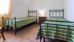 A room with two beds, a nightstand, and a window with curtains. - Holiday Home 'Podere Simonetta - A13' with Shared Pool, Shared Garden and Wi-Fi (Cecina)