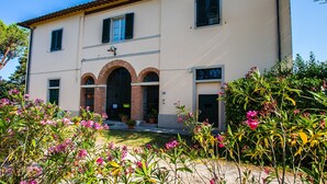 A two-story building with a tiled roof, a central entrance with an arched doorway, and a small balcony. - Holiday Home 'Podere Simonetta - A13' with Shared Pool, Shared Garden and Wi-Fi (Cecina)