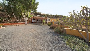 Un bâtiment avec une allée gravillonnée, entouré d’arbres et de plantes.