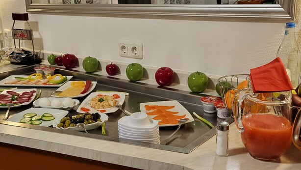Ein reichhaltiges Buffet mit verschiedenen Speisen, darunter Obst, Gemüse und ein Krug Saft.