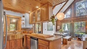 Una cocina amplia con armarios de madera, una isla central y un gran ventanal con vistas a un bosque.