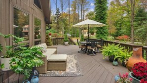 Una terraza de madera con mobiliario exterior, incluyendo un sofá, una mesa y sillas.