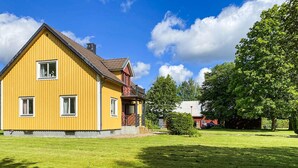 A yellow two-story house with a balcony, surrounded by a well-maintained lawn and trees. - Awesome home in Hyltebruk with WiFi (Hyltebruk)