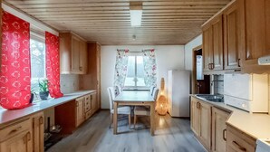 A compact kitchen with wooden cabinets, a dining table, and a refrigerator. - Awesome home in Hyltebruk with WiFi (Hyltebruk)