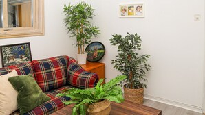 A living room with a plaid sofa, a wooden coffee table, and various potted plants. - Awesome home in Hyltebruk with WiFi (Hyltebruk)