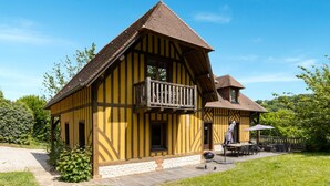 Ett traditionellt hus med korsvirkesfasad, en balkong, en grillplats och en uteplats med utemöbler.