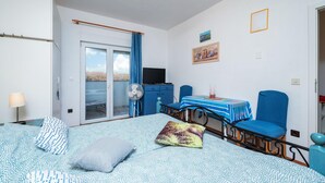 A bedroom with a bed, a desk, a chair, a fan, a TV, and a balcony with a view. - 1 bedroom cozy apartment in Barbariga (Barbariga)