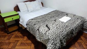 Un dormitorio con una cama de madera, una mesita de noche verde y una colcha estampada.