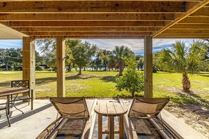 Zona relax esterna coperta con vista su un paesaggio erboso e alberi.