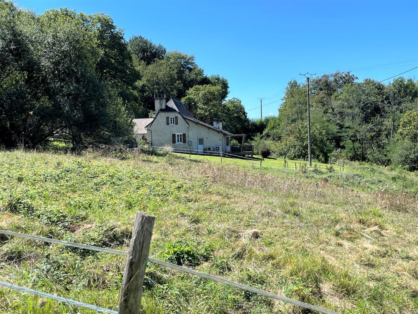 Una casa con techo inclinado, rodeada de un campo cubierto de césped y árboles.