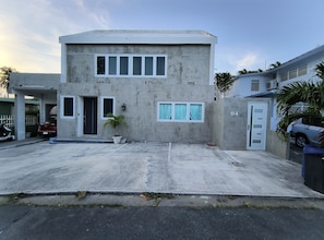 Un immeuble de deux étages avec un garage, un pot de fleurs et le numéro 94 sur la porte.