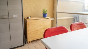 A room with a wooden desk, a potted plant, red chairs, and a window with a view. - SE031 - Senigallia, two-room apartment facing the sea at the Piramidi residence (Cesano)