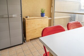 Una habitación con escritorio de madera, una planta en maceta, sillas rojas y ventana con vistas.
