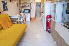 Un espacio habitable pequeño con sofá, kitchenette y una zona de comedor.