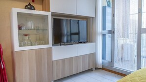 A modern room with a built-in TV, a glass cabinet with kitchenware, and a sliding glass door to the outside. - SE031 - Senigallia, two-room apartment facing the sea at the Piramidi residence (Cesano)