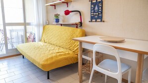 A room with a yellow sofa, a white chair, a wooden table, a red lamp, and a blue wall hanging. - SE031 - Senigallia, two-room apartment facing the sea at the Piramidi residence (Cesano)