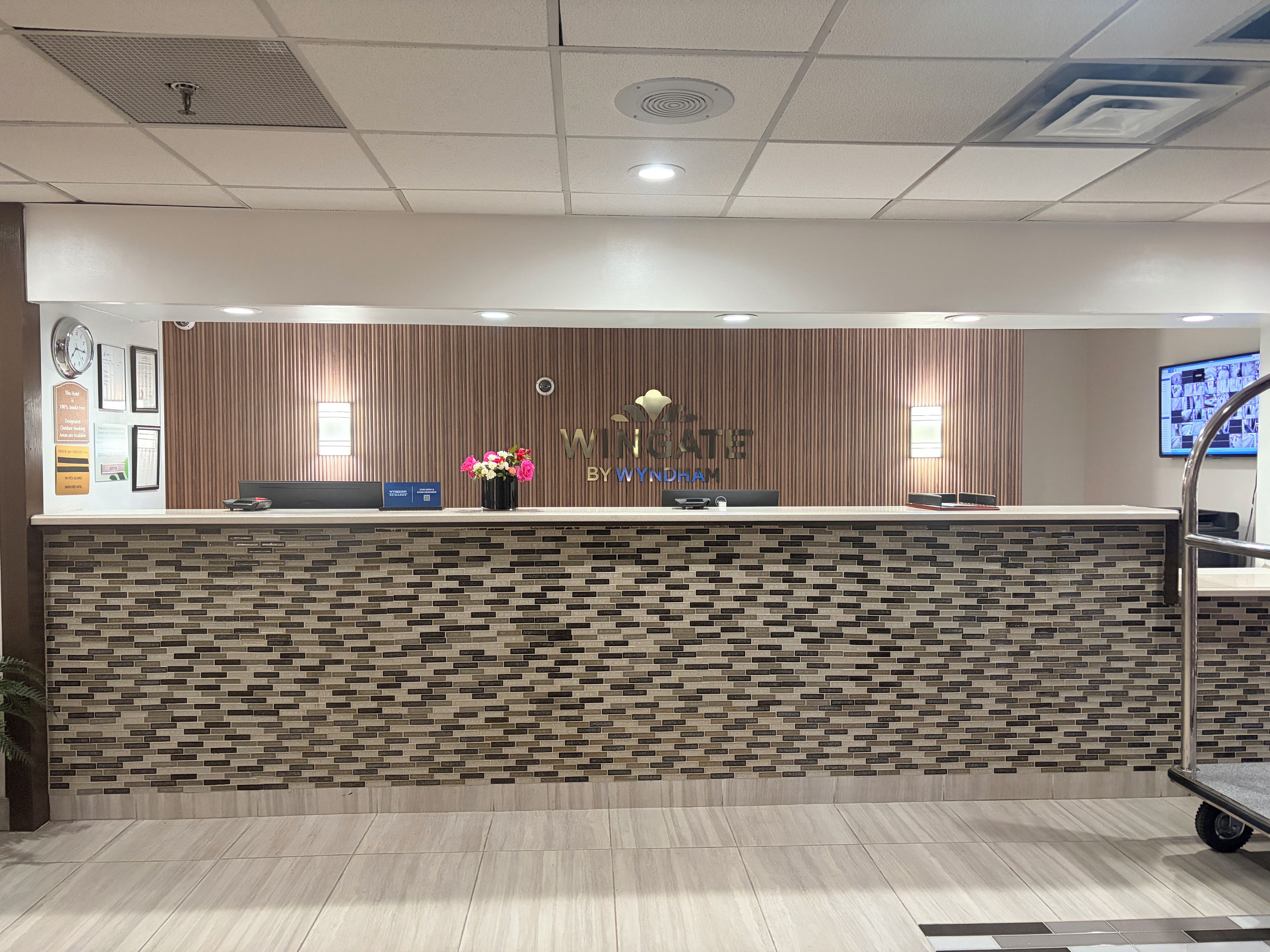 Una reception dal design moderno, con una parete decorata e uno schermo digitale.