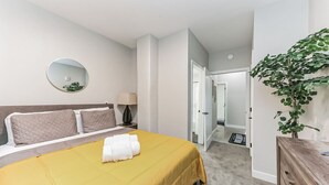 Een hotelkamer met een bed, een bedlamp, een spiegel en een plant.