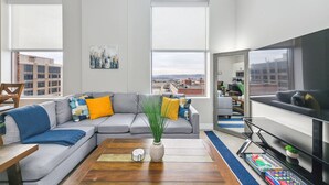Een moderne woonkamer met een grijze modulaire bank, een salontafel en een grote flatscreen-tv.