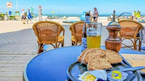 Een tafel met een fles Blanche de Narmer, een glas geel drankje, sneetjes brood, boter en een zoutvaatje.