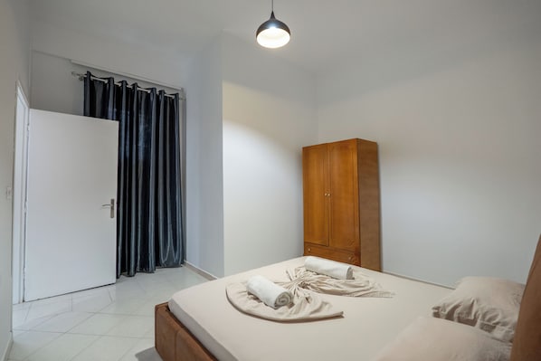 A bedroom with a bed, a wardrobe, and a door with curtains.