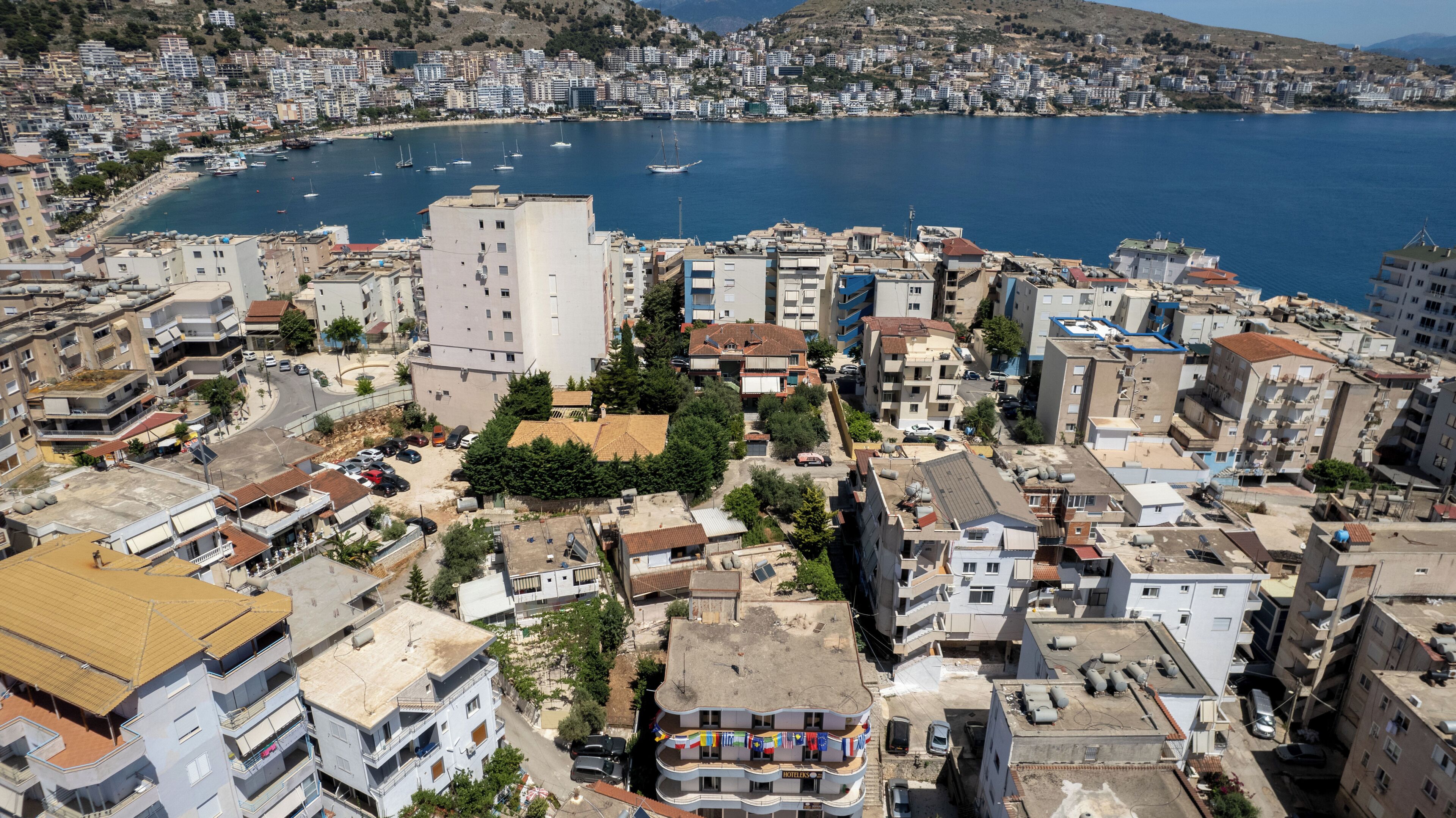 A coastal cityscape with a prominent hotel featuring balconies and a view of the sea.
