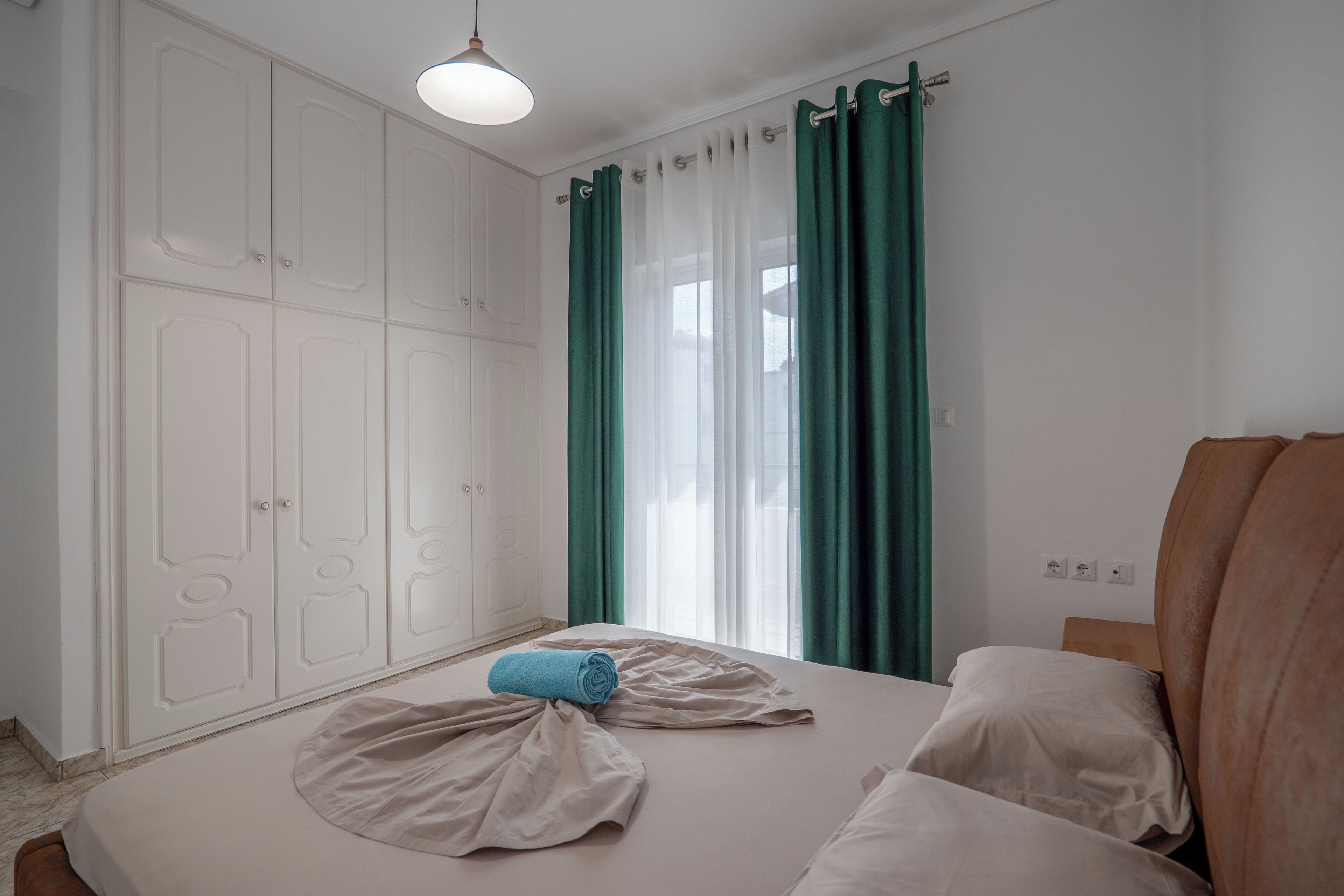 A bedroom with a bed, a wardrobe, and a window with curtains.