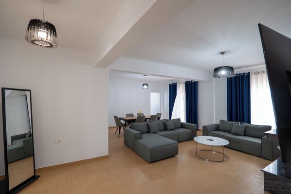 A modern living room with a sectional sofa, a round coffee table, and a dining area with chairs and a table.